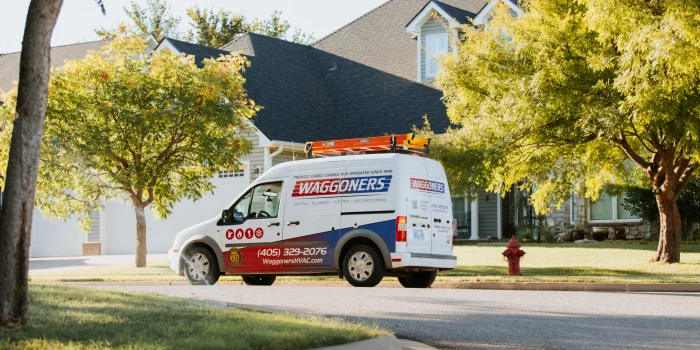Waggoner Onsite A Waggoners-branded van, showcasing their "About Us" ethos, is parked on a suburban street near a house. It features a ladder on top and contact information on the side, ready to serve the neighborhood's needs.